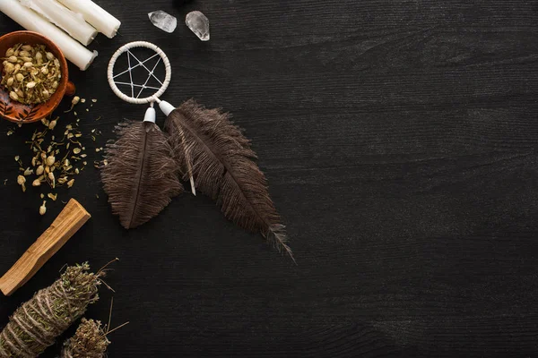 Vue de dessus du capteur de rêves, bâtons de taches avec des cristaux magiques et des bougies sur la surface en bois sombre — Photo de stock