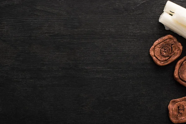 Top view of candles and clay amulets on dark wooden background with copy space — Stock Photo