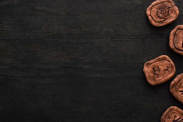 Top view of shamanic clay amulets with symbols on dark wooden surface — Stock Photo