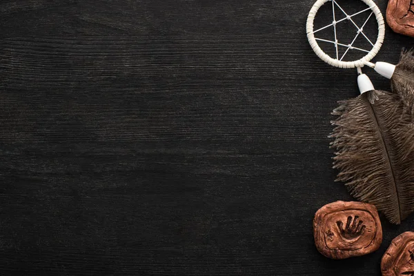 Top view of clay amulets and shamanic dreamcatcher on dark wooden surface — Stock Photo