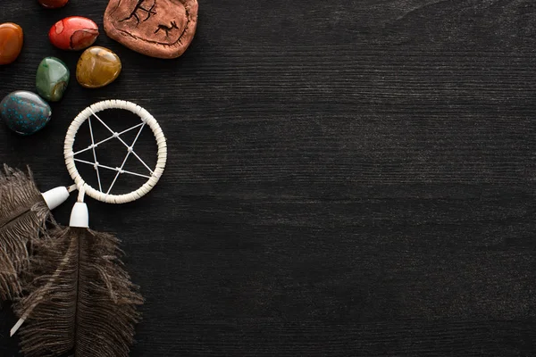 Vista superior del atrapasueños, piedras adivinadoras y runa mágica sobre fondo de madera oscura - foto de stock