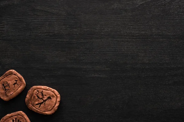 Vue du dessus des amulettes d'argile avec des symboles sur fond en bois noir avec espace de copie — Photo de stock