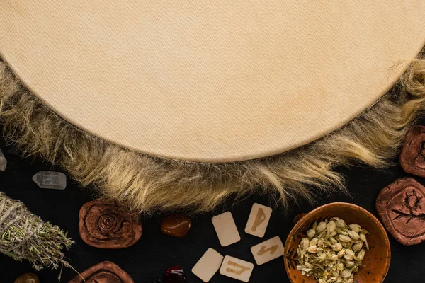 Vue de dessus du tambourin, des amulettes d'argile et des herbes isolées sur noir — Photo de stock