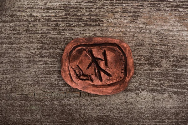 Top view of clay talisman with symbol on wooden background — Stock Photo