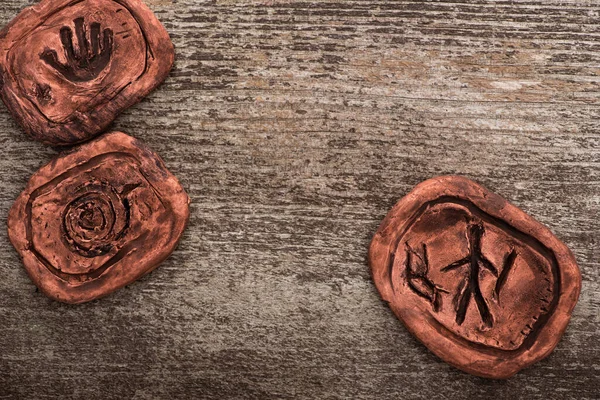 Vista dall'alto dei simboli sui talismani di argilla sciamanica sulla superficie di legno — Foto stock