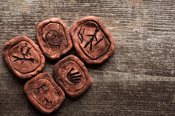 Top view of clay talismans with signs on wooden background with copy space — Stock Photo