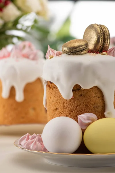 Селективный фокус вкусного пасхального торта с золотыми французскими макаронами и безе на глазури возле яиц — стоковое фото