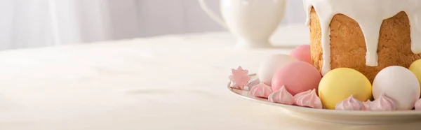 Delicious Easter cake near meringue with pink and white eggs on plate, panoramic shot — Stock Photo