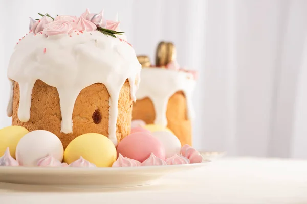 Enfoque selectivo de deliciosos pasteles de Pascua decorados con merengue cerca de huevos de colores en los platos - foto de stock