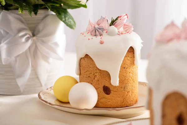 Foco selectivo de pastel de Pascua festivo decorado con merengue cerca de huevos pintados en platos y flores - foto de stock