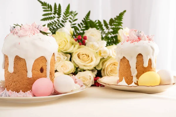 Leckere Osterkuchen mit Baiser mit bunten Eiern auf Teller in der Nähe von Blumen dekoriert — Stockfoto