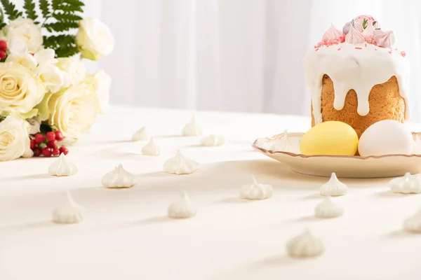 Délicieux gâteau de Pâques avec des œufs sur assiette près des fleurs et de la meringue — Photo de stock