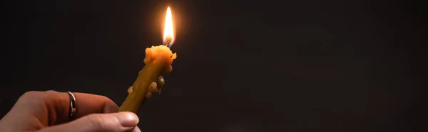 Vista ritagliata di donna che tiene la candela della chiesa in fiamme nel buio, colpo panoramico — Foto stock