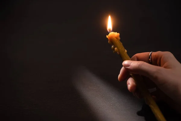 Cropped view of woman holding burning church candle in dark — Stock Photo