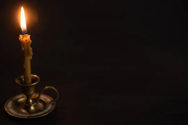 Church candle in candlestick burning in dark — Stock Photo