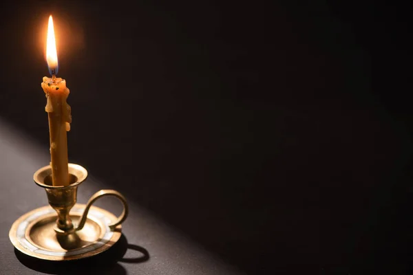 Church candle in candlestick burning in dark with sunlight — Stock Photo