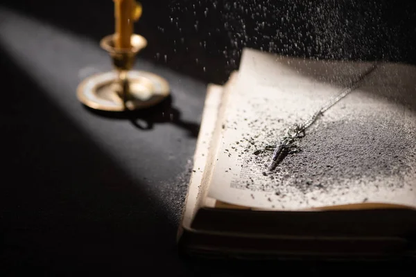 Selective focus of candlestick near bible with catholic cross and ashes in dark with sunlight — Stock Photo