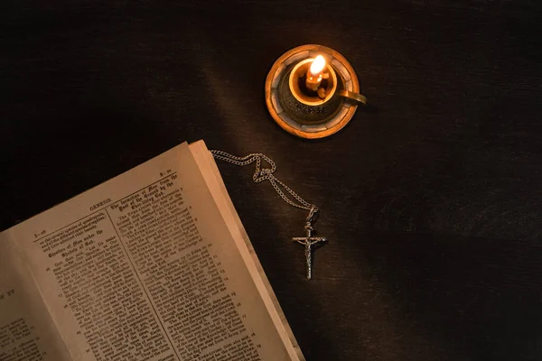 KYIV, UKRAINE - 17 JANVIER 2020 : vue de dessus de la bible sainte ouverte avec croix et bougie sur fond sombre — Photo de stock