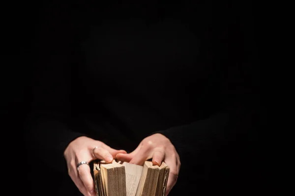 Vista recortada de la mujer sosteniendo la sagrada Biblia aislada en negro - foto de stock