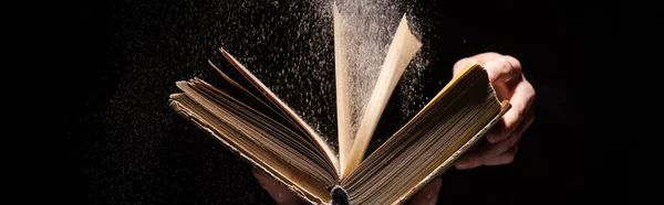 Cropped view of woman holding holy bible with dust on black background, panoramic shot — Stock Photo
