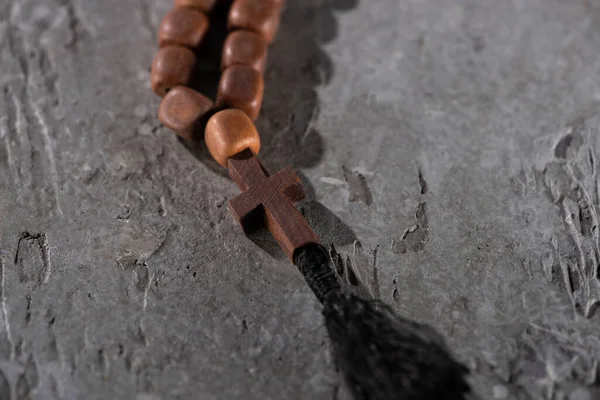 Wooden rosary with cross on grey textured surface — Stock Photo
