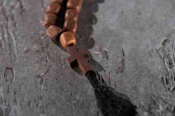 Wooden rosary with cross on grey textured surface — Stock Photo