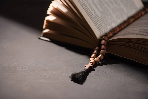 Sainte Bible avec chapelet sur fond noir foncé avec lumière du soleil — Photo de stock