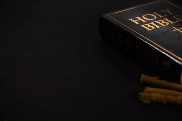 Enfoque selectivo de la Biblia santa y velas sobre fondo negro oscuro - foto de stock