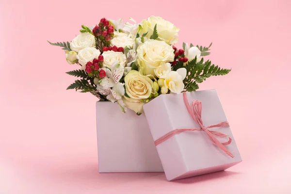 Bouquet de fleurs dans une boîte cadeau festive avec arc sur fond rose — Photo de stock