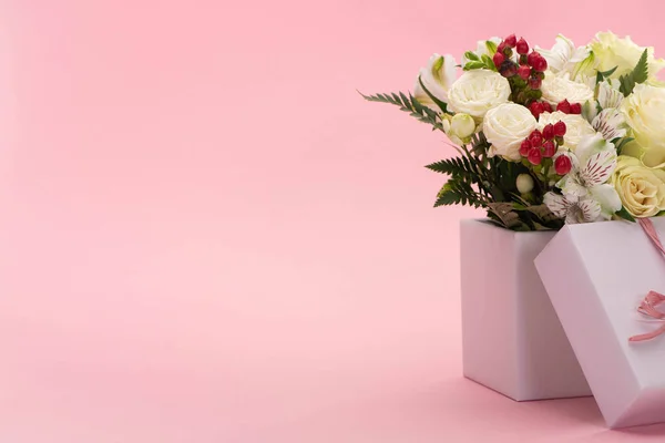 Bouquet of flowers in festive gift box with bow on pink background — Stock Photo