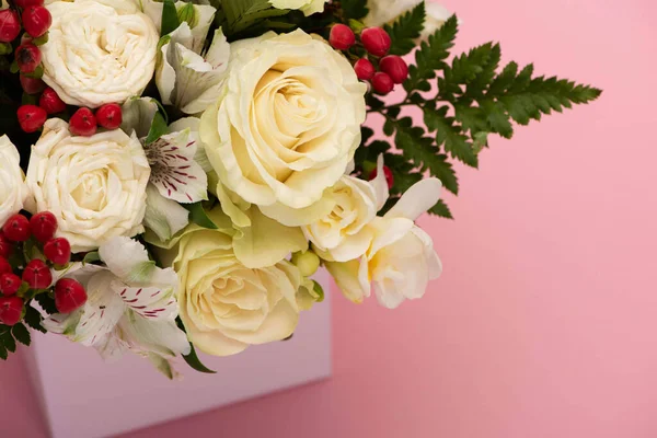 Vista de cerca del ramo de flores en la caja de regalo festiva sobre fondo rosa - foto de stock