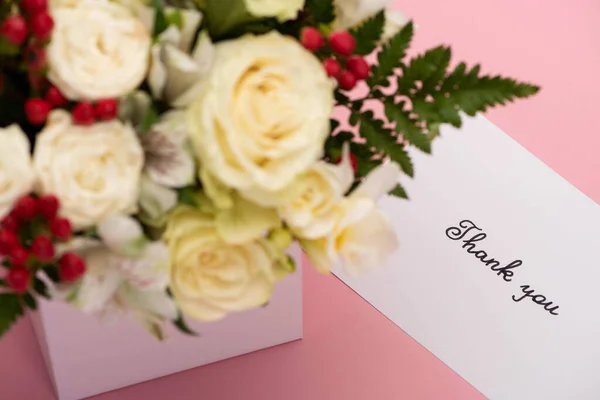 Selective focus of bouquet of flowers in festive gift box near thank you greeting card on pink background — Stock Photo