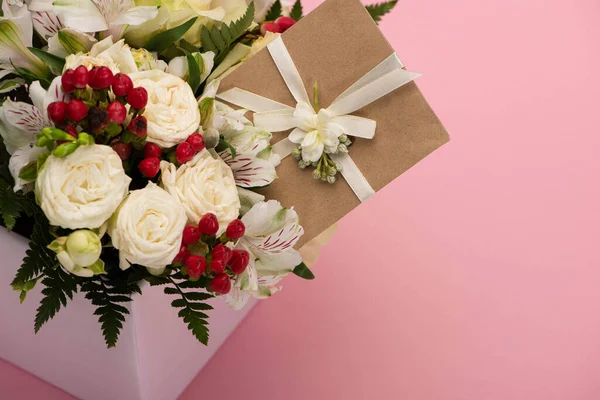 Bouquet of flowers in festive gift box with greeting card on pink background — Stock Photo