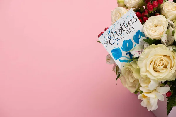 Ramo de flores en caja de regalo festiva con tarjeta de felicitación del día de las madres sobre fondo rosa — Stock Photo