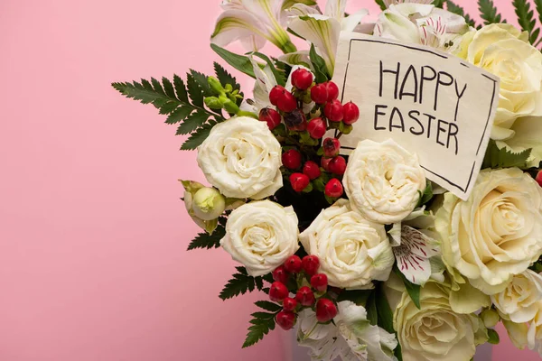 Ramo de flores en caja de regalo festiva con feliz tarjeta de felicitación de Pascua sobre fondo rosa - foto de stock