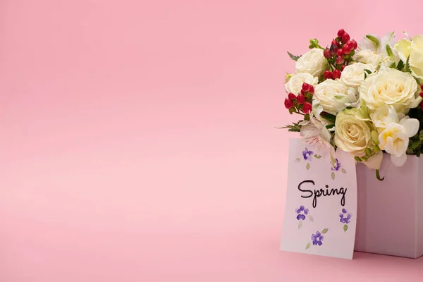 Bouquet of flowers in festive gift box with spring greeting card on pink background — Stock Photo