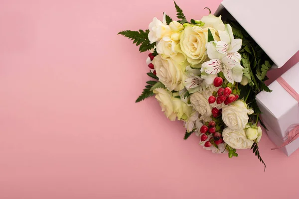 Vista superior do buquê de flores em caixa de presente festivo com arco sobre fundo rosa — Fotografia de Stock