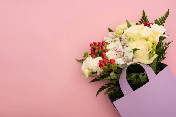 Вид на букет цветов в фиолетовом бумажном мешке на розовом фоне — стоковое фото
