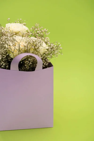 Ramo fresco de flores en bolsa de papel violeta aislado en verde - foto de stock