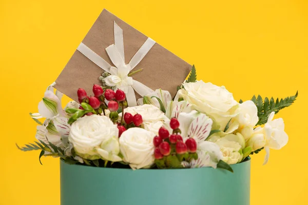 Ramo de flores frescas de primavera en caja de regalo festiva con tarjeta de felicitación aislada en amarillo — Stock Photo