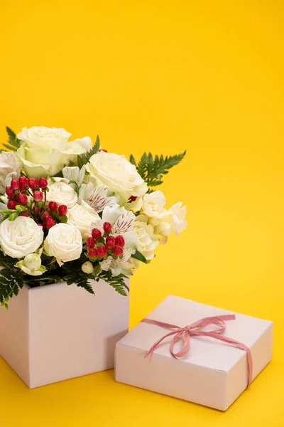 Ramo de flores frescas de primavera en caja de regalo festiva sobre fondo amarillo — Stock Photo