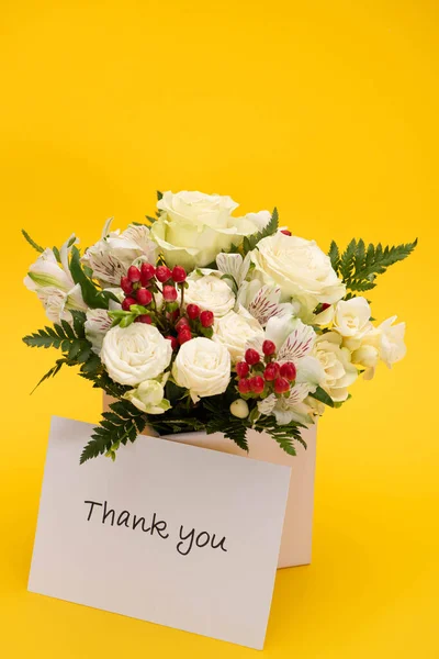 Primavera ramo fresco de flores en caja de regalo festivo cerca de la tarjeta de agradecimiento sobre fondo amarillo - foto de stock