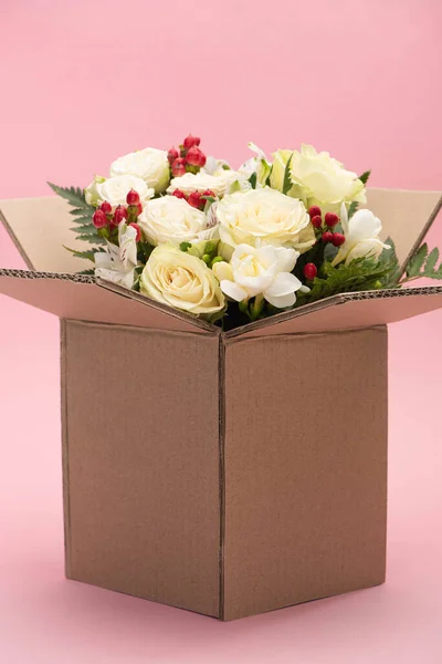 Bouquet of flowers in carton box on pink background — Stock Photo