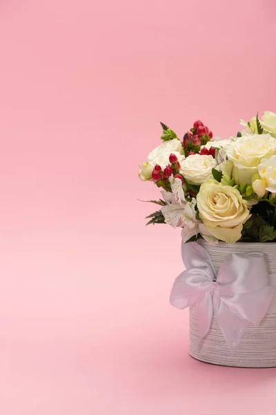 Букет квітів у святковій подарунковій коробці з бантом на рожевому фоні — стокове фото