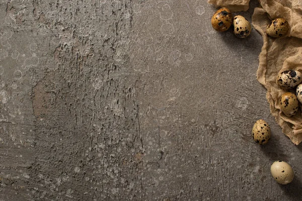 Vue de dessus des œufs de caille sur gaze brune sur fond texturé gris — Photo de stock