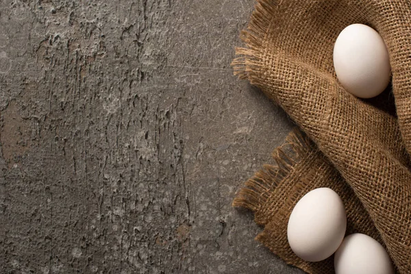 Vue du dessus des œufs de poulet blancs sur sac sur fond texturé gris — Photo de stock