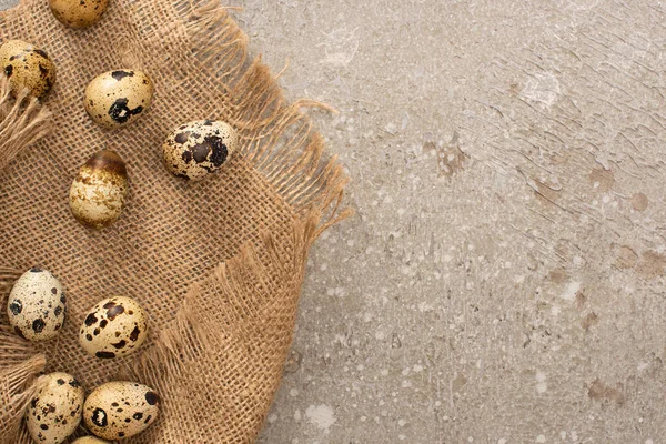 Top view of quail eggs on sackcloth on grey cement background — Stock Photo