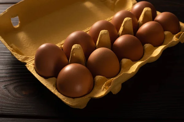 Uova di pollo marroni in vassoio d'uovo su sfondo di legno marrone — Foto stock