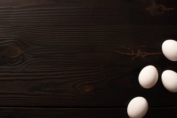 Vista superior de huevos de pollo blancos en la superficie de madera oscura - foto de stock