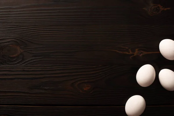 Top view of white chicken eggs on dark wooden surface — Stock Photo